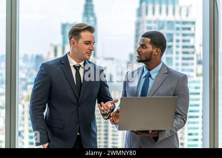 Die beiden Geschäftsleute in formeller Kleidung stehen an den Fenstern. Stockfoto