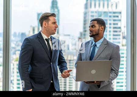Die beiden Geschäftsleute in formeller Kleidung stehen an den Fenstern. Stockfoto