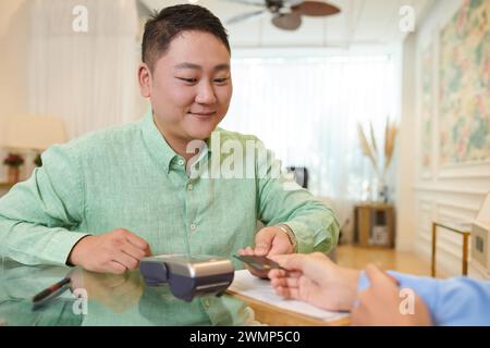 Lächelnder Rezeptionist akzeptiert Zahlung vom Kunden des Spa-Salons Stockfoto