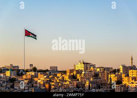 Wunderschönes Stadtbild bei Sonnenuntergang von Amman, Jordanien mit jordanischer Flagge im Wind Stockfoto