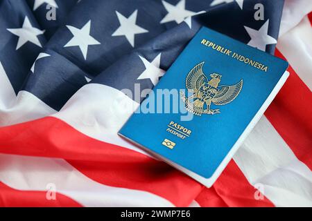 Pass der blauen Republik Indonesien auf dem Hintergrund der Nationalflagge der Vereinigten Staaten aus nächster Nähe. Tourismus und Diplomatie Stockfoto