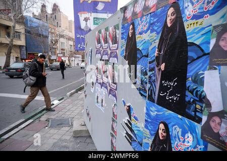 Teheran, Iran. Februar 2024. Ein iranischer Mann läuft neben den Wahlplakaten der Kandidaten, die bei den bevorstehenden Parlamentswahlen antreten, auf einer Straße in Teheran. Die iranischen Wähler werden am 1. März ihre Stimmzettel abgeben, um neue Mitglieder des iranischen parlaments und der Expertenversammlung auszuwählen, einem wichtigen Gremium, das den obersten Führer des Landes ernennt. (Kreditbild: © Rouzbeh Fouladi/ZUMA Press Wire) NUR REDAKTIONELLE VERWENDUNG! Nicht für kommerzielle ZWECKE! Stockfoto