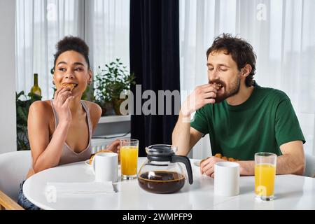 Wunderschönes, abwechslungsreiches Paar in Homewear, das ihr köstliches Frühstück zu Hause genießt Stockfoto