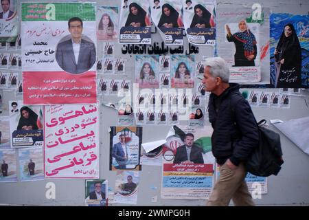Teheran, Iran. Februar 2024. Ein iranischer Mann läuft neben den Wahlplakaten der Kandidaten, die bei den bevorstehenden Parlamentswahlen antreten, auf einer Straße in Teheran. Die iranischen Wähler werden am 1. März ihre Stimmzettel abgeben, um neue Mitglieder des iranischen parlaments und der Expertenversammlung auszuwählen, einem wichtigen Gremium, das den obersten Führer des Landes ernennt. (Kreditbild: © Rouzbeh Fouladi/ZUMA Press Wire) NUR REDAKTIONELLE VERWENDUNG! Nicht für kommerzielle ZWECKE! Stockfoto
