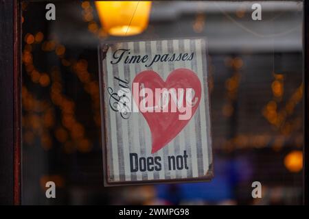 Altes Metallschild im Fenster eines Restaurants mit der Aufschrift: Die Zeit vergeht, aber die Liebe nicht. Stockfoto