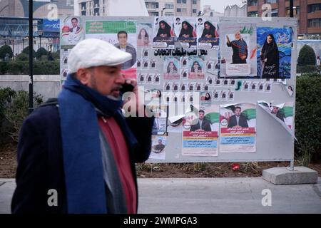 Teheran, Iran. Februar 2024. Ein iranischer Mann läuft neben den Wahlplakaten der Kandidaten, die bei den bevorstehenden Parlamentswahlen antreten, auf einer Straße in Teheran. Die iranischen Wähler werden am 1. März ihre Stimmzettel abgeben, um neue Mitglieder des iranischen parlaments und der Expertenversammlung auszuwählen, einem wichtigen Gremium, das den obersten Führer des Landes ernennt. (Kreditbild: © Rouzbeh Fouladi/ZUMA Press Wire) NUR REDAKTIONELLE VERWENDUNG! Nicht für kommerzielle ZWECKE! Stockfoto