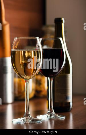 Französischer weiß- und Rotwein in Gläsern mit Blasen auf dem Tisch eine Küche mit einer Weinflasche im Hintergrund Stockfoto