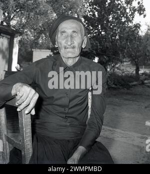 1970er Jahre, historisch, Porträt eines älteren Mannes aus Capri, Italien, der Tradtional-Kopfbedeckung trägt und draußen auf einem Stuhl sitzt. Stockfoto