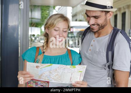 Glückliche Touristen, die mit fröhlichem Ausdruck auf der Karte suchen Stockfoto