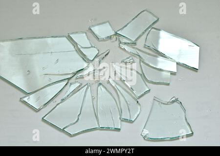 Scherben aus Glassplittern verschiedener Formen und Größen liegen auf einem grauen Hintergrund. Stockfoto