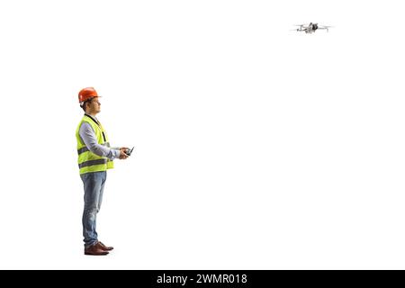 Ingenieur in einer Sicherheitsweste, die eine Drohne mit einer Fernbedienung auf weißem Hintergrund fliegt Stockfoto