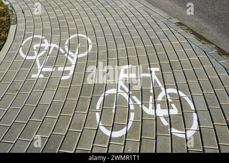 Weiße Fahrradsymbole auf grauen Fahrbahnsteinen, Fahrradschilder auf dem Fahrradweg Stockfoto