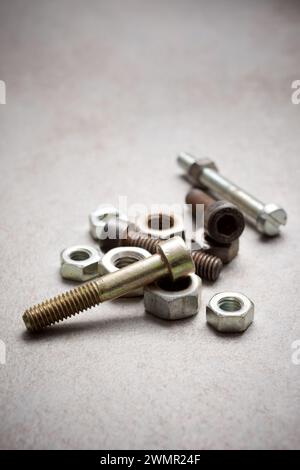 Nahaufnahme einer Gruppe von Metallmuttern und -Schrauben auf einer Werkbank Stockfoto