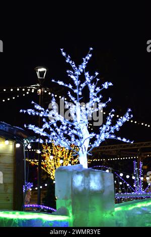 Helle festliche Beleuchtung in der Stadt am Neujahrstag. Künstliche Bäume mit grünen LED-Leuchten. Weihnachtsbeleuchtung. Stockfoto