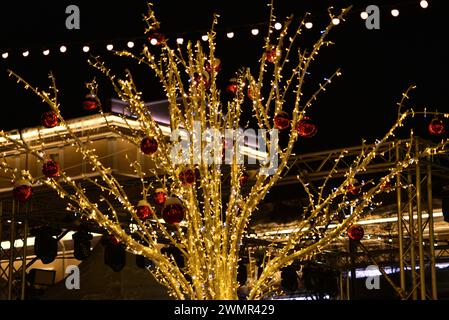 Leichte festliche Beleuchtung in der Neujahrsstadt. Künstliche Bäume mit gelben Lichtern. Weihnachtsgirlande. Stockfoto