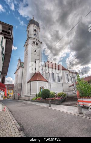 Nesselwang, Deutschland - 06. Juli 2023: Weitwinkel-Eckansicht der St. Andreas-Kirche mit Glockenturm in Nesselwang von Norden zum Himmel. Stockfoto