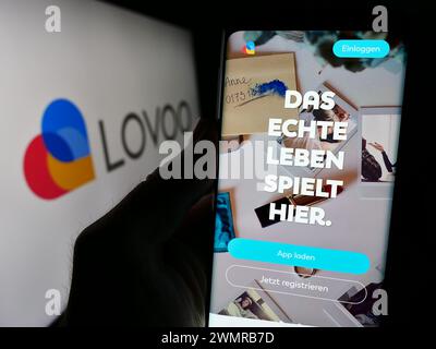 Person, die ein Handy hält, mit Webseite der deutschen Online-Dating-Plattform LOVOO vor dem Logo. Konzentrieren Sie sich auf die Mitte des Telefondisplays. Stockfoto