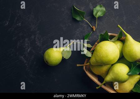 Gartenarbeit. Herbsternte. Grüne reife Birnen in einer Schachtel auf dunklem Hintergrund. Birne aus dem Garten. Köstliche Birnen aus der Nähe. Draufsicht, flach. Copyspa Stockfoto