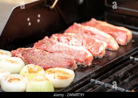Rindersteaks und Zwiebeln, die auf dem Grill brutzeln, perfekt für eine köstliche Mahlzeit Stockfoto