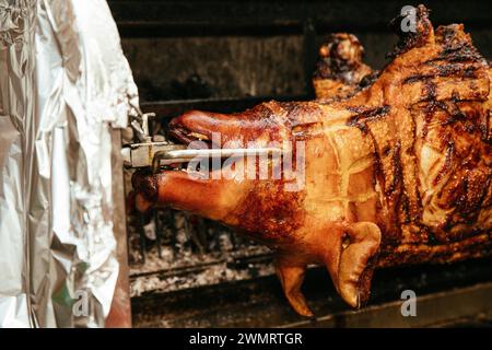 Ganzes Schwein mit knuspriger Haut, das auf einem Spieß gebraten wird Stockfoto