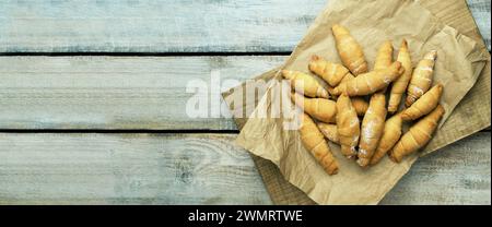 Frische Croissants auf Pergamentpapier. Knuspriges Croissant. Französisches Konditorkonzept. Frische Croissants auf Tisch, auf Tischhintergrund, Draufsicht flach, mit Stockfoto