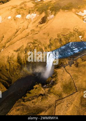 Drohnenaufnahme des Skgafoss-Wasserfalls, der majestätische Landschaft, isländische Landschaft mit nordischer Natur schafft. Spektakuläre arktische Kaskade, die von felsigen Hügeln herunterläuft, natürliche Umgebung in island. Stockfoto