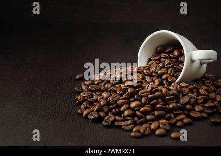 Duftender Morgenkaffee. Favoritenprüfungen. Gewürzter Kaffee. Kaffeekonsumenten sind auf einem dunklen Holzhintergrund verstreut. Kaffeetasse und Bohnen auf einem schwarzen Stockfoto