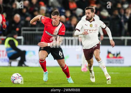 Luton, Großbritannien. Februar 2024. Luton Town Ross Barkley kämpft um den Ball gegen Bernardo Silva von Manchester City während des Spiels der 5. Runde des Luton Town FC gegen Manchester City FC Emirates FA Cup in der Kenilworth Road, Luton, England, Großbritannien am 27. Februar 2024 Credit: Every Second Media/Alamy Live News Stockfoto