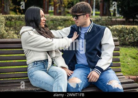 Ein wütendes lateinamerikanisches Studentenmädchen lehnt ihren kaukasischen Freund ab, der draußen auf einer Bank sitzt Stockfoto