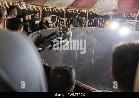 Medan, Nord-Sumatra, Indonesien. Februar 2024. Ein Mann unterhält Nachtmarktbesucher auf der Devil's Barrel Attraction, Besucher geben ihm auch Geld während der Devil's Barrel Racing Attraction. (Credit Image: © Kartik Byma/SOPA Images via ZUMA Press Wire) NUR REDAKTIONELLE VERWENDUNG! Nicht für kommerzielle ZWECKE! Stockfoto