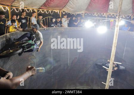 Medan, Nord-Sumatra, Indonesien. Februar 2024. Ein Mann unterhält Nachtmarktbesucher auf der Devil's Barrel Attraction, Besucher geben ihm auch Geld während der Devil's Barrel Racing Attraction. (Credit Image: © Kartik Byma/SOPA Images via ZUMA Press Wire) NUR REDAKTIONELLE VERWENDUNG! Nicht für kommerzielle ZWECKE! Stockfoto