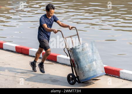 SAMUT PRAKAN, THAILAND, 11. Februar 2024, Ein Portier läuft entlang einer überfluteten Marktstraße Stockfoto