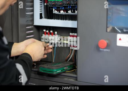 Elektriker, der Leitungen im Schaltschrank von Industrieanlagen anschließt. Industrielle elektrische Schalttafel. Selektiver Fokus. Stockfoto