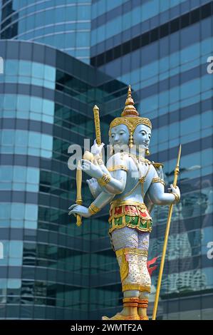 Eine blau-goldene Statue von Jatulokbal, eine thailändische Ikonographie der Lokapalas, die die vier Himmelsrichtungen verteidigt, steht vor Wolkenkratzern Stockfoto