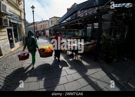 Bukarest, Rumänien - 27. Februar 2024: Zwei Blumenhändlerinnen tragen ihre Körbe mit bunten Blumen zum Verkaufszentrum in der Altstadt von Bukarest. Quelle: Lucian Alecu/Alamy Live Stockfoto