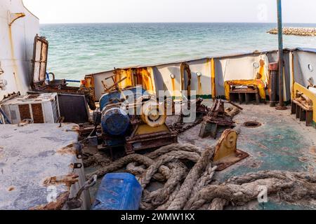 Zerstörtes und rostiges Deck eines Frachtschiffes, das an Land gewaschen wurde, mit Winde, Seilen, Maschinen und Ausrüstung, am Strand von Al Hamriyah, den Vereinigten Arabischen Emiraten. Stockfoto