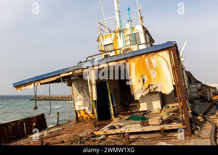 Abgerissenes und rostiges Deck eines Frachtschiffes mit alter Brücke, Mast, Antennen und Maschinen, das am Strand von Al Hamriyah in Umm Al Quwain, Vereinigte Arabische Emirate an Land gespült wurde Stockfoto