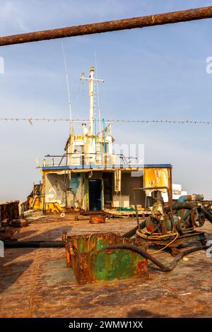 Abgerissenes und rostiges Deck eines Frachtschiffes mit alter Brücke, Mast, Antennen und Maschinen, das am Strand von Al Hamriyah in Umm Al Quwain, Vereinigte Arabische Emirate an Land gespült wurde Stockfoto