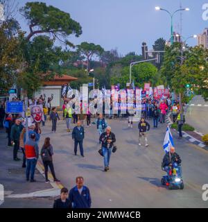 Haifa, Israel - 24. Februar 2024: Menschen marschieren mit verschiedenen Zeichen und Flaggen aus Protest gegen die Regierung und rufen zu Neuwahlen auf. Haifa, Isra Stockfoto