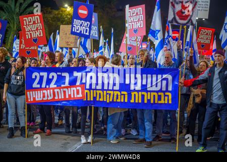 Haifa, Israel - 24. Februar 2024: Menschen marschieren mit verschiedenen Zeichen und Flaggen aus Protest gegen die Regierung und rufen zu Neuwahlen auf. Haifa, Isra Stockfoto