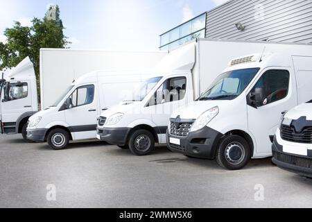 Weiße Lieferwagen auf dem Parkplatz vor dem Eingang eines Lagers im Verteilerzentrum Stockfoto