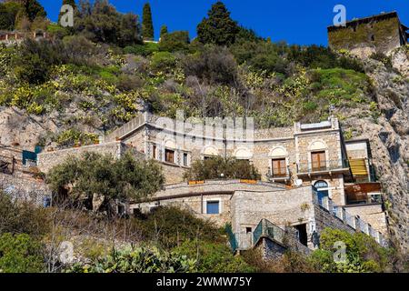 Taormina, Sizilien, Italien - 15. Februar 2023: Sizilianische Steinhäuser am felsigen Ufer des Ionischen Meeres in Taormina über den Städten Giardini Naxos und Villagonia Stockfoto