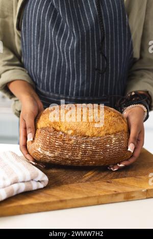 Eine junge Afroamerikanerin hält einen frisch gebackenen Brotlaib mit Kopierraum Stockfoto