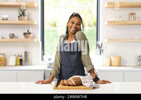 Eine junge Afroamerikanerin steht mit einem selbstbewussten Lächeln in einer hellen Küche Stockfoto