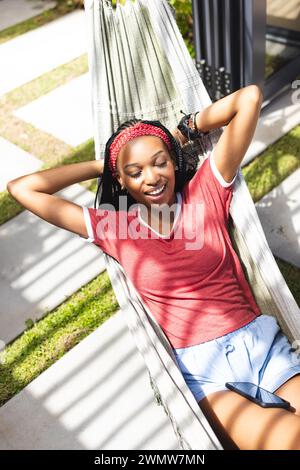 Eine junge Afroamerikanerin entspannt sich in einer Hängematte und genießt Musik Stockfoto