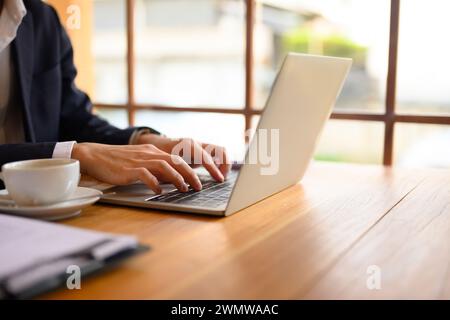 Zugeschnittener Schuss junger Geschäftsmann, der Hände auf einem Laptop schreibt und im Café arbeitet Stockfoto