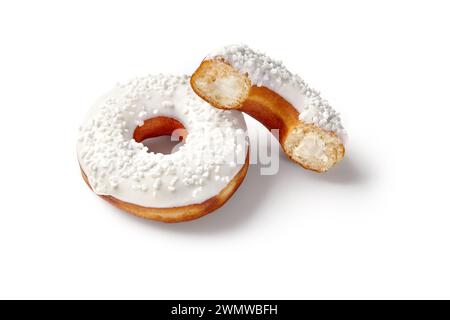 Zwei süße weiche Donuts mit cremiger Füllung, weißer Vanilleglasur und Zuckerstreuseln auf nahtlosem weißem Hintergrund. Beliebte Süßwaren Stockfoto