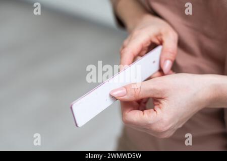 Maniküre- und Pedikürenfeile in einer Hand isoliert auf weißem Hintergrund. Kosmetisches Werkzeug Stockfoto