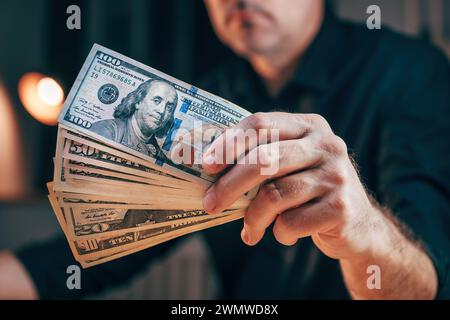 Nahaufnahme einer männlichen Hand mit Dollarscheine, eines Geschäftsmannes mit amerikanischem Geld, einer Handvoll Bargeld und bereit, in unternehmerische Projekte zu investieren Stockfoto