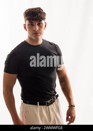 Ein Foto, das einen Mann mit schwarzem Hemd und braunen Shorts zeigt. Der Mann steht draußen in einem legeren Outfit und sieht entspannt und bequem aus. Stockfoto